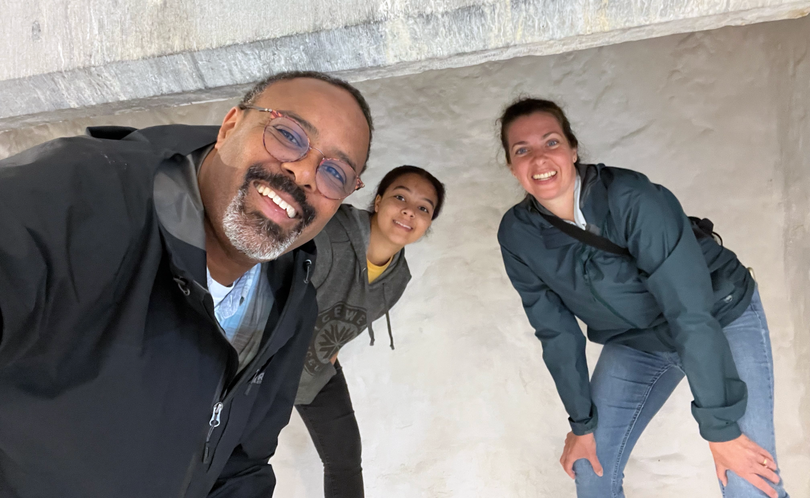 Dr. Horton smiles at the camera in a selfie, with his daughter, Lacie, and wife, Tiffany, leaning in behind him against a pale stone wall.