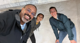 Dr. Horton smiles at the camera in a selfie, with his daughter, Lacie, and wife, Tiffany, leaning in behind him against a pale stone wall.