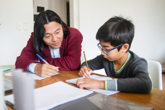 A dad helps his son with school work.