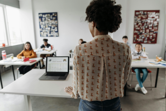 Teacher at the front of a classroom and her students in the classroom