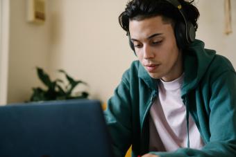 Male high school student focused on online coursework at home