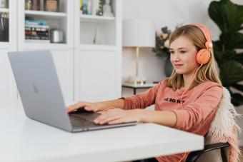Student studying online at home with headphones and a laptop
