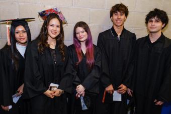 Diverse group of UT High School graduates in caps and gowns backstage, celebrating completion of their online diploma program