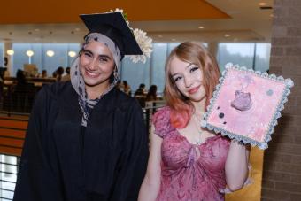 Two smiling graduates with their beautifully decorated mortar board caps