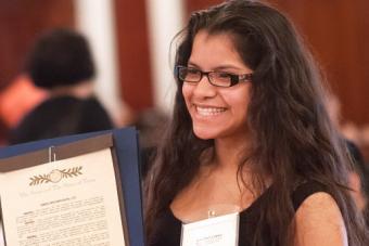 Migrant program student poses with her award certificate